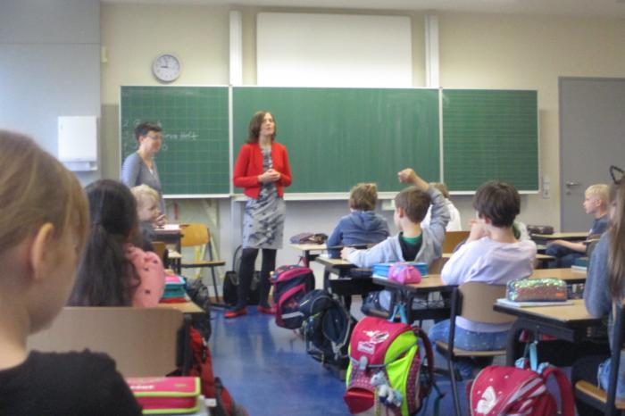 Schüler*innen in einer Klasse, vorne stehen zwei Frauen