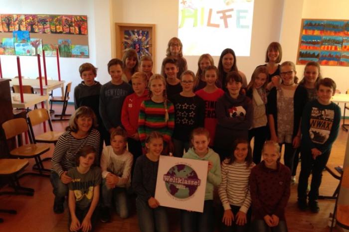 Gruppenfoto der Schüler*innen der Seeadlerklasse in Wismar, die das Weltklasse! Siegel in die Kamera halten. 